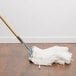 A Carlisle white knitted cotton wet mop head with a wooden handle.