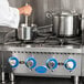 A chef stirring a pot on a Globe countertop gas hot plate.
