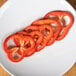 A white plate with a close-up of sliced red bell peppers using the Robot Coupe 27087 3/16" Slicing Disc.