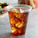 A Solo clear plastic squat cup with a clear drink, ice, and a lemon.