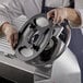 A person using an Avantco blade removal tool to hold a circular metal plate.