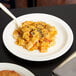 A close-up of a white Cambro polycarbonate plate with pasta.