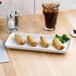 A Tuxton rectangular eggshell china tray with food on a table next to a glass of iced tea.