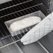 A loaf of bread in a Chicago Metallic bread loaf pan in an oven.