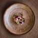 A RAK Porcelain Timber Brown porcelain deep coupe plate with food on a table.
