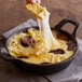 A person dipping a cracker into a pot of cheese fondue.