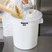 A woman pouring pasta into a Rubbermaid ingredient storage container with a sliding lid.