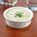 A Tuxton eggshell embossed rim china bowl filled with soup and parsley.