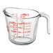 A clear glass Anchor Hocking measuring cup with a red handle and red measurements.