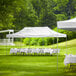 A white Backyard Pro canopy set up in a grassy area with tables and chairs.