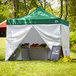 A green Backyard Pro canopy with white walls set up on grass.