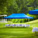 A Backyard Pro Courtyard blue canopy set up over tables with white tablecloths in a grassy area.