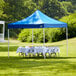 A blue Backyard Pro Courtyard canopy set up over a table with a white tablecloth on grass