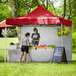 A man and woman standing in a red Backyard Pro tent.