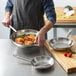 A person cooking food in a Vigor stainless steel frying pan.