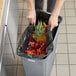 A woman holding a Lavex trash bag full of vegetables.