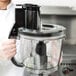 A woman holding a Waring 4 qt. batch bowl food processor.