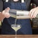 A hand using an Acopa Boston shaker to pour a cocktail into a glass.