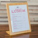 A Cal-Mil bamboo menu displayette with a menu on a wood stand.