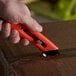 A person holding a Pacific Handy Cutter with a red handle.