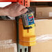 A hand holding a yellow Pacific Handy Cutter Blade Bank on a shelf.