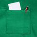 A Chef Revival Kelly Green bib apron with a pocket holding a pen and paper.