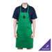 A man wearing a Kelly green Chef Revival apron with a black logo on a counter in a professional kitchen.