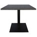 A Grosfillex dark grey square concrete table top on a black table base.