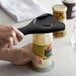 An OXO Good Grips jar opener being used to open a jar of food on a counter.