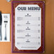 A brown menu with an angled marble border on a table with a fork and knife.