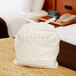 A white plastic laundry bag with a logo on a bed.