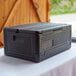 A CaterGator Dash black plastic box with a flip down lid on a table.