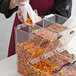 A person using a Choice stackable candy dispenser to pour candy into a container.