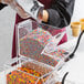 A person pouring colorful sprinkles into a clear plastic container.