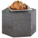 A plate of food on a Cal-Mil Ashwood oak wood hexagon riser on a wooden table.