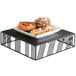 A black Cal-Mil metal riser holding a tray of pastries.