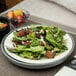 A gray insulated base with a plate of salad, fruit, and nuts.