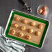 A half size silicone baking mat on a baking sheet with muffins and eggs.