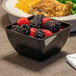 A black Dinex SAN plastic bowl filled with blackberries and raspberries.