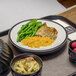 A black Dinex induction base with a plate of rice and chicken on a tray.