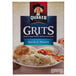 A bowl of Quaker grits with a biscuit and bread on the side.