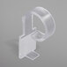 A clear plastic table skirt clip with a white hook and loop attachment.