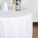 A white table with a white table skirt clipped on and a silver thermos on it.