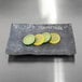 An Elite Global Solutions Basalt rectangular melamine plate with slices of lemons and limes on it.