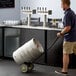 A man pushing a barrel on a Regency keg and pail truck.