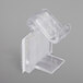 A close-up of a Snap Drape clear plastic table skirt clip with a hook and loop attachment.