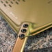 A GI Metal gold anodized aluminum square perforated pizza peel with a metal handle.