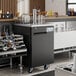 An Avantco black double tap kegerator on a bar counter.