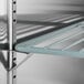 An Avantco black metal shelf with a blue metal bar on it.