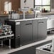 An Avantco black kegerator with four beer taps on a counter.